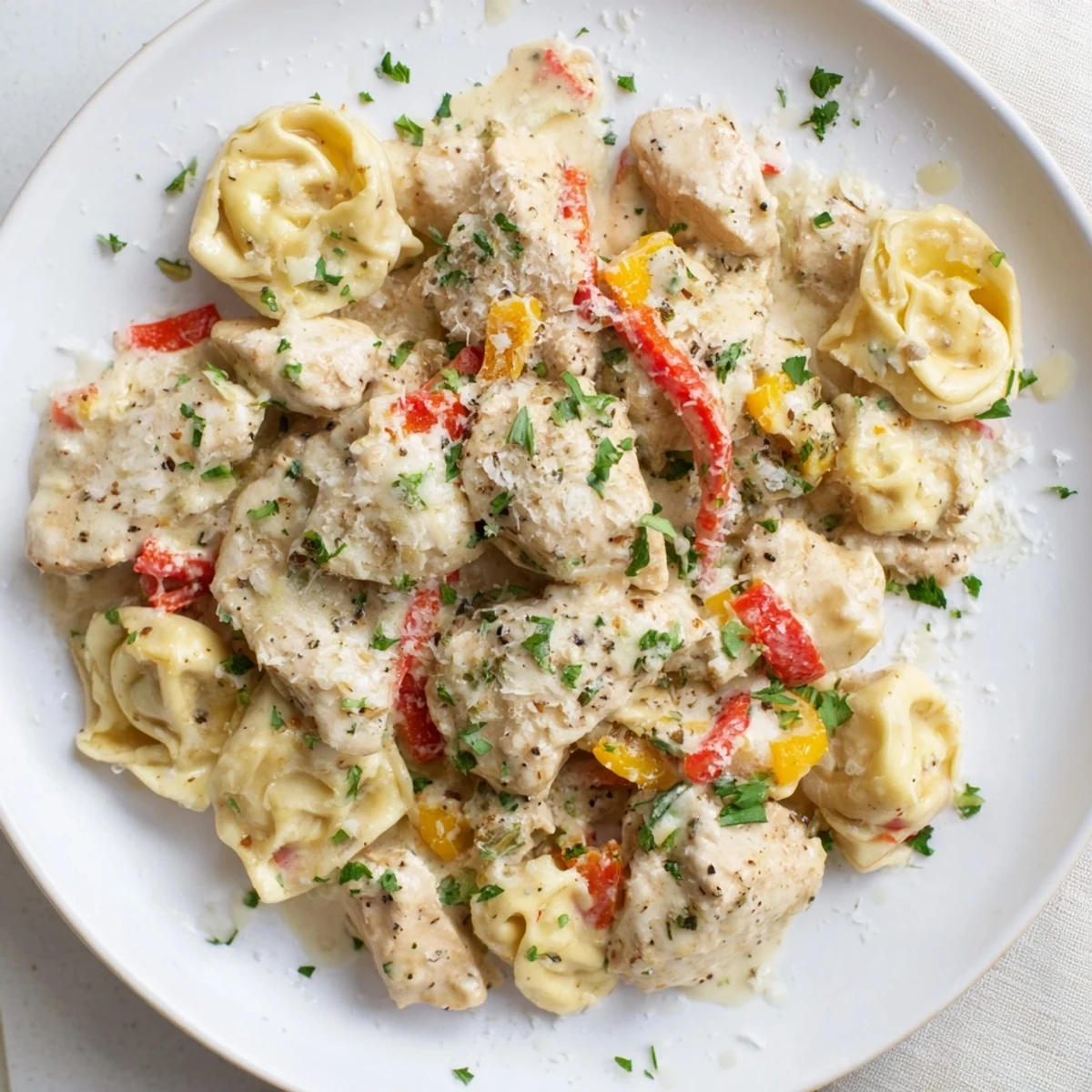 Close-up of vibrant Zesty Cajun Garlic Parmesan Chicken Tortellini; chicken pieces nestled in a rich sauce.