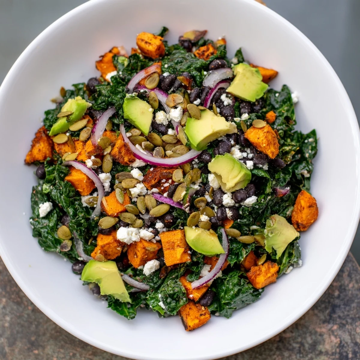 Vibrant massaged kale salad with sweet potato, black beans, and lime dressing, ready to enjoy.