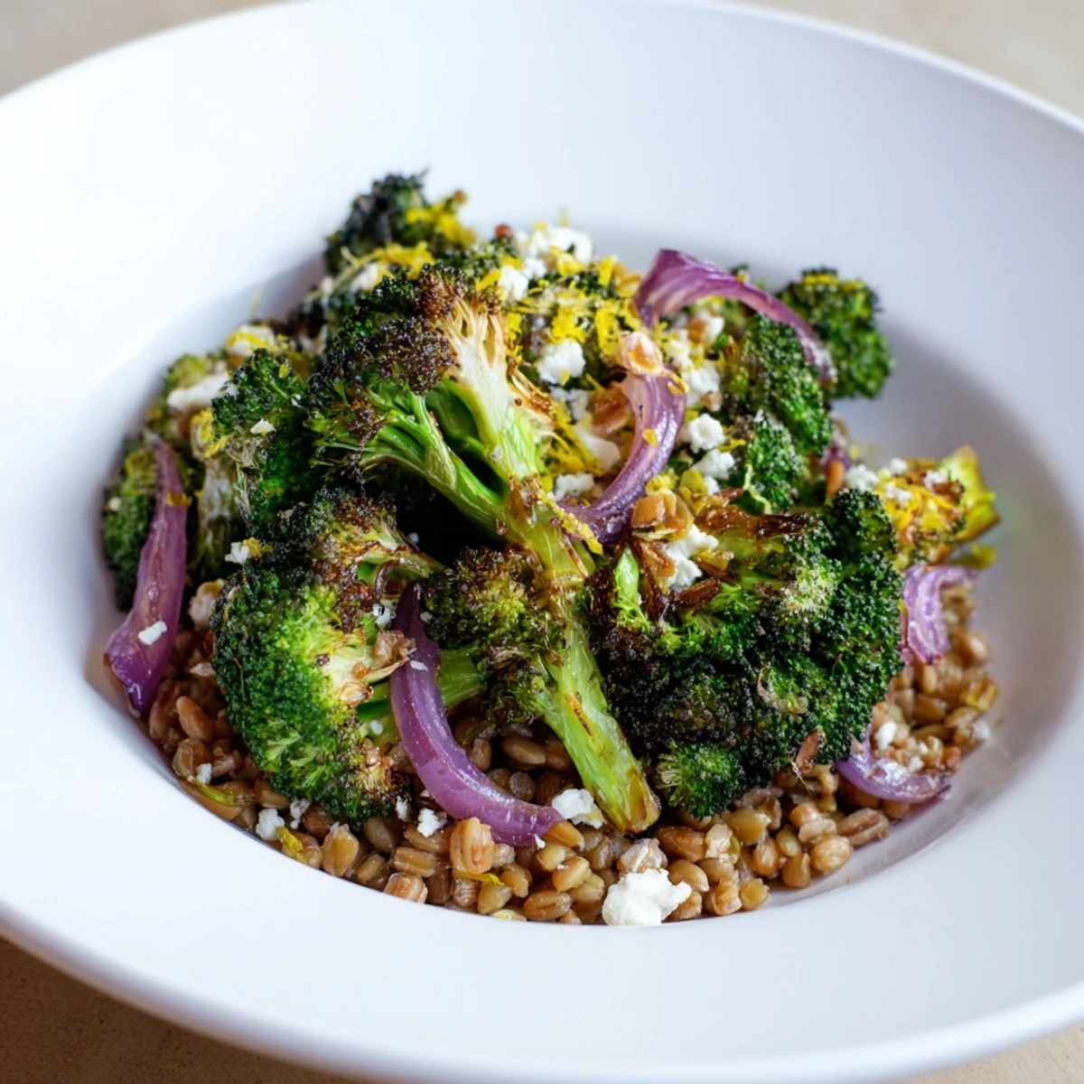 A vibrant bowl of warm roasted broccoli served atop farro, perfect for a vegetarian meal.