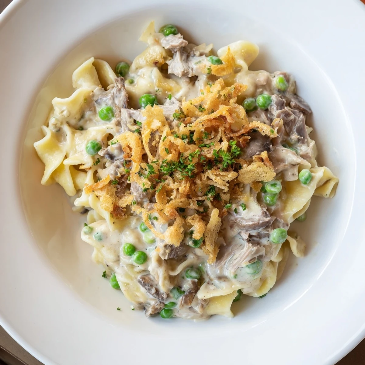 A close-up shot of creamy Tuna Noodle Casserole, garnished with golden-brown fried onions.