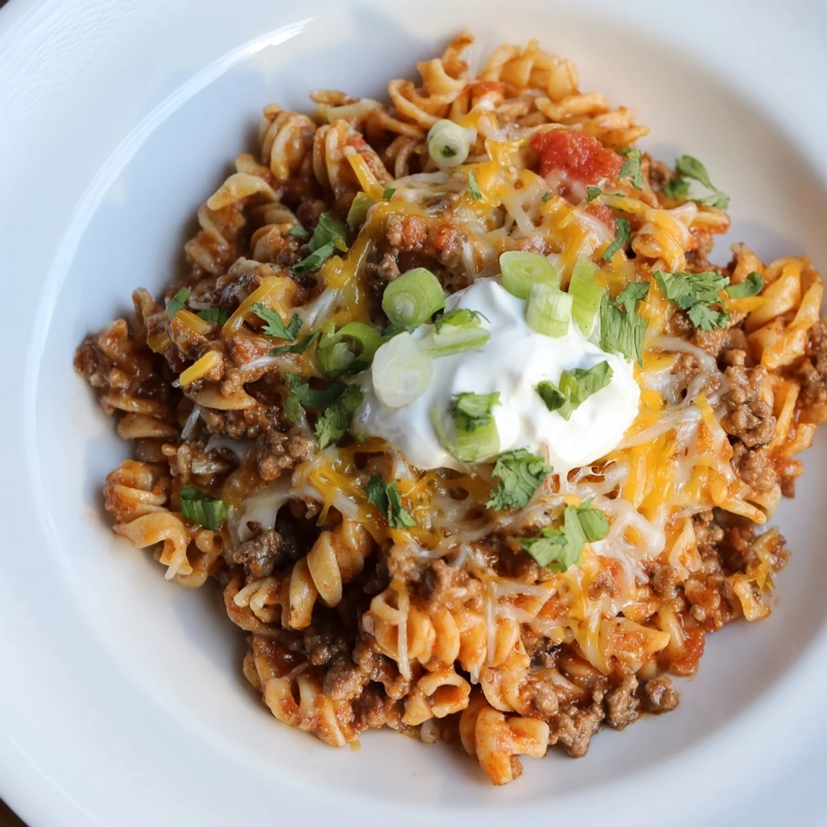 Easy Beef Enchilada Pasta, a one-pot meal, features bubbly melted cheese over pasta and seasoned ground beef.