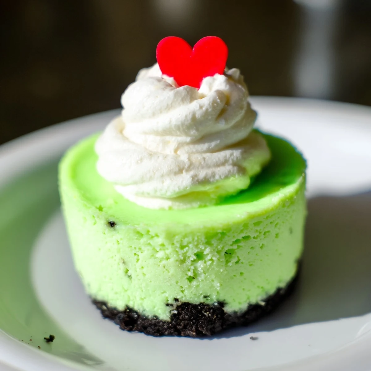 Close-up of creamy, neon green Grinch mini cheesecakes garnished with festive sprinkles for Christmas.
