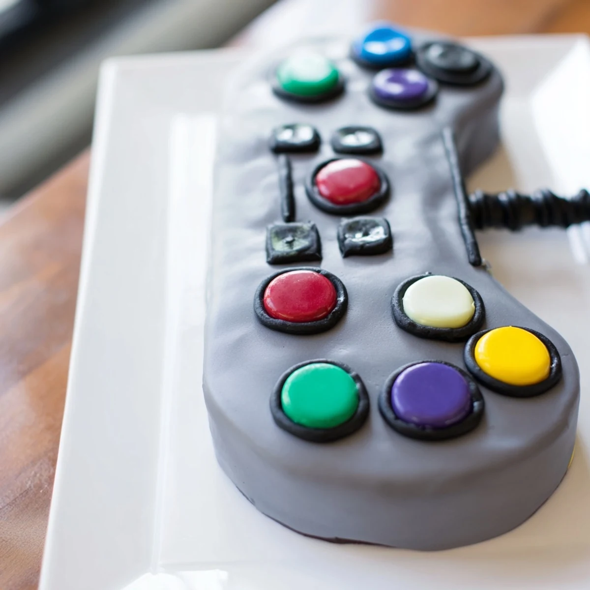 A colorful Pixel Perfect Video Game Controller Board cake with vibrant buttercream frosting and candy buttons.