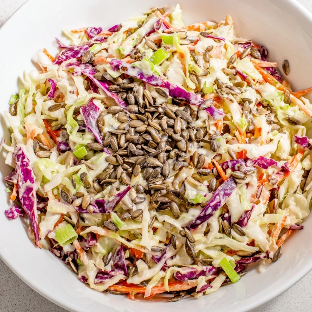 A close-up of a vibrant crunchy coleslaw salad, topped with sunflower seeds, ready for your next meal.