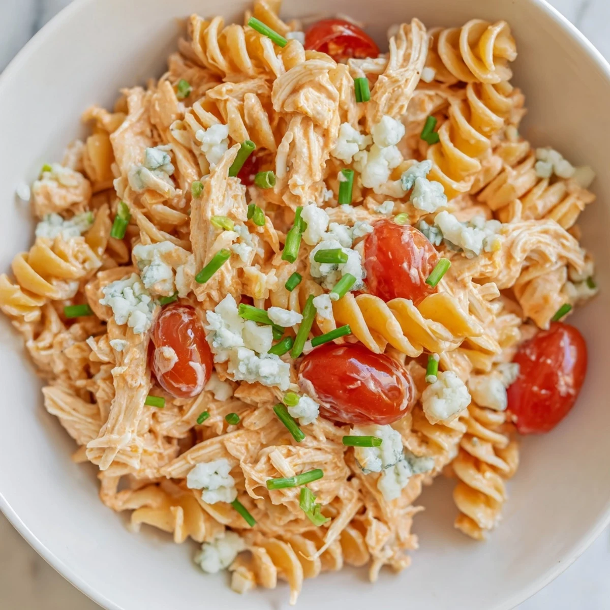 Vibrant Buffalo Chicken Pasta Salad with rotini, shredded chicken in tangy sauce, crisp celery, red peppers, and creamy ranch dressing in a bowl.