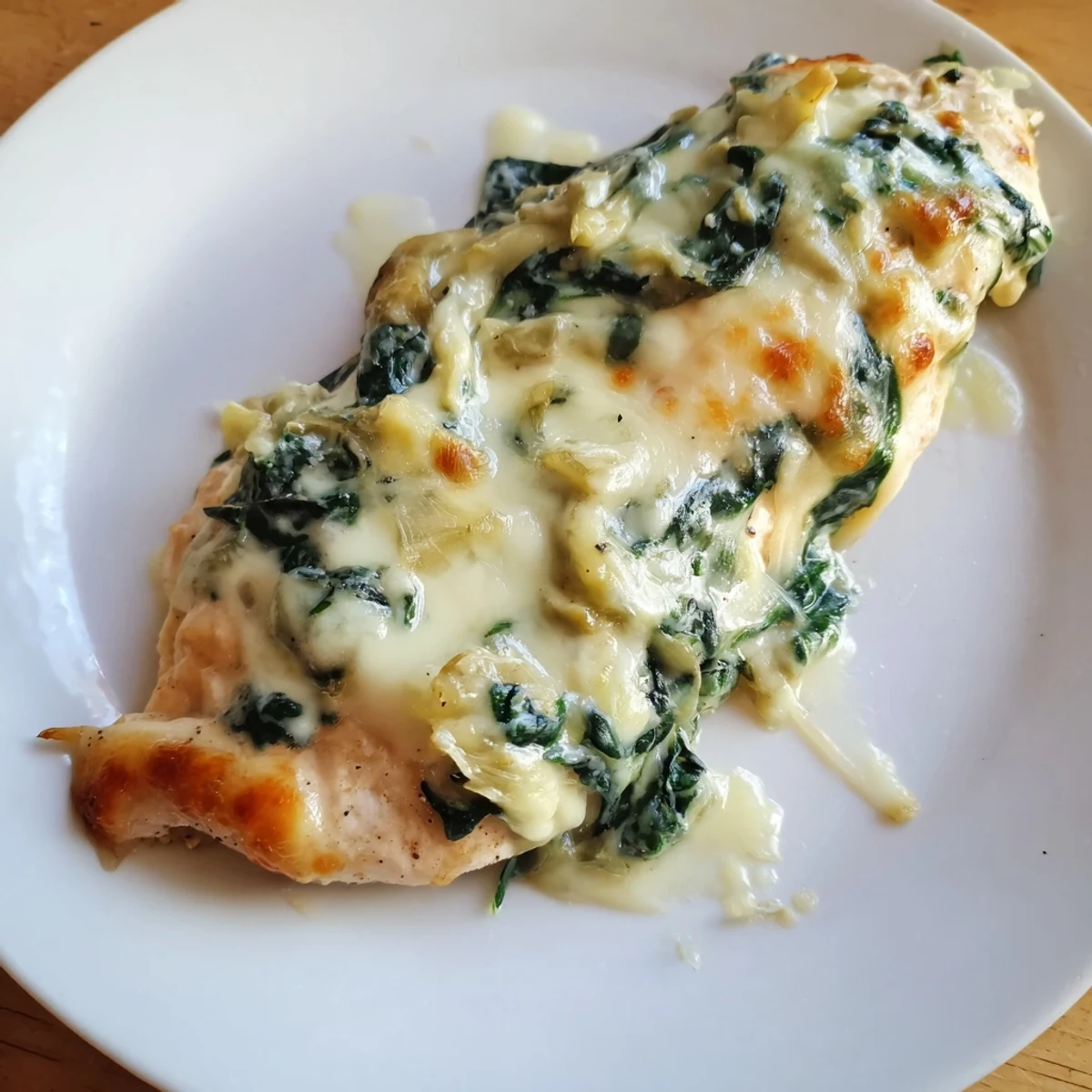Golden, bubbling Spinach & Artichoke Chicken Bake fresh from the oven in a ceramic dish.