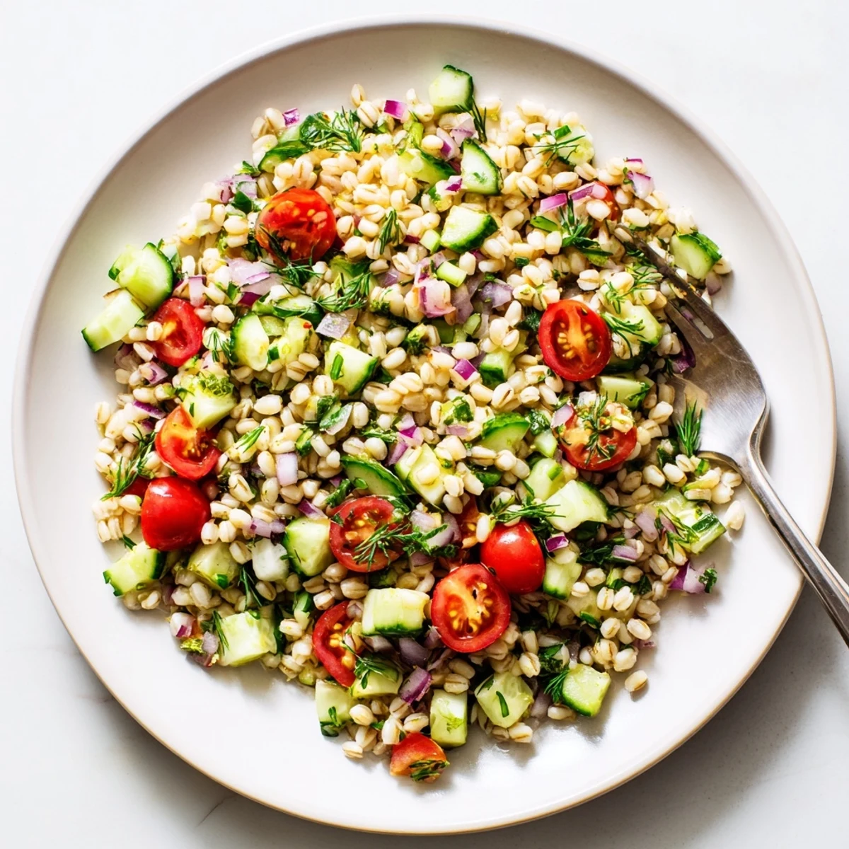 A close-up of vibrant Barley and Herb Salad featuring chewy pearl barley, fresh parsley, mint, and dill tossed with cherry tomatoes and cucumber.