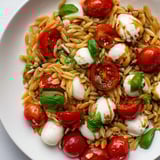 A colorful bowl of Caprese Orzo Salad, showcasing tender pasta and fresh herb garnishes, ready to serve.
