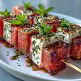 Colorful watermelon feta mint skewers drizzled with olive oil and balsamic glaze for a party platter.