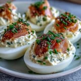 Creamy deviled eggs filled with smoked salmon and chives, topped with everything bagel seasoning for a flavorful bite.