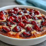 Warm Fresh Cherry Clafoutis, golden brown with tender cherries and vanilla aroma.