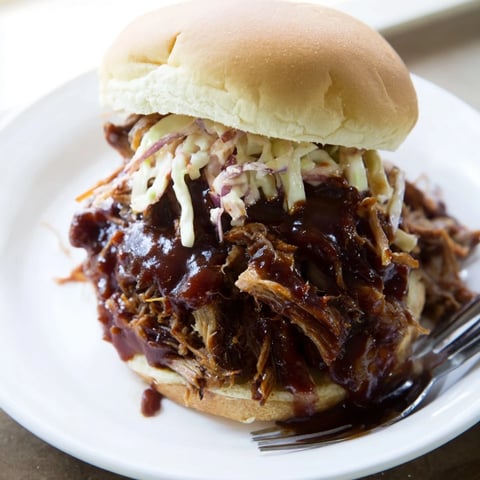 Tender slow cooker BBQ pulled pork sandwiches stacked on fluffy buns with coleslaw.  