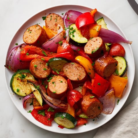 Golden-brown sheet-pan roasted veggies and sausage with colorful peppers and onions, ready to eat.