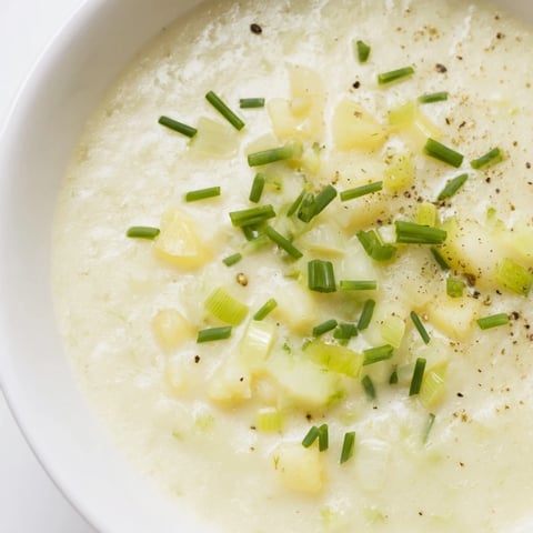 A steaming bowl of Potato Leek Soup, garnished with chives, a hearty, comforting meal.