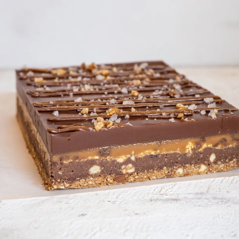 Golden, gooey 7-Layer Magic Bars topped with a sea salt caramel drizzle, ready to enjoy.