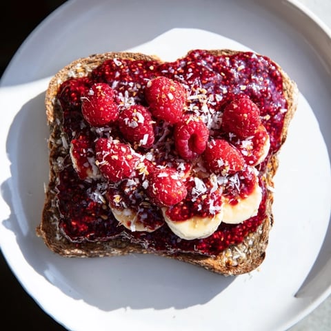 Heaping spoonfuls of homemade raspberry chia jam glistening on warm, toasted bread for breakfast.