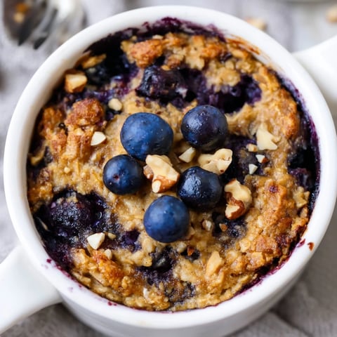 A freshly baked serving of Blueberry Baked Oats, golden brown, with plump, burst blueberries in every bite.
