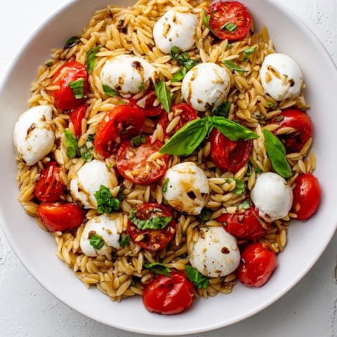 Vibrant Caprese Orzo Salad featuring juicy tomatoes and creamy mozzarella, drizzled with balsamic dressing.
