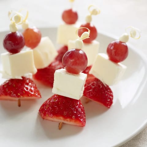 Party-ready Santa Hat Fruit and Cheese Platter shows colorful fruit arranged like festive hats; a tasty appetizer.