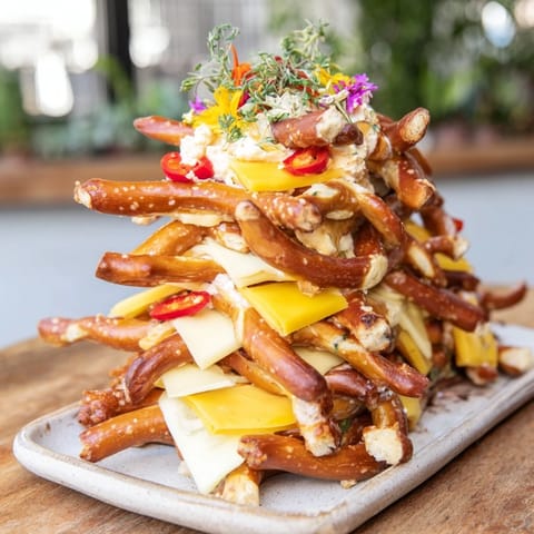 Savory Rustic Log Cabin appetizer depicts pretzel rods and cheddar cheese stacked high for party fun.