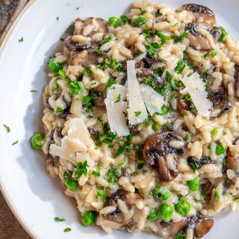 Steaming Orzo Mushroom Risotto-Style with earthy mushrooms and peas in a rustic ceramic bowl.  