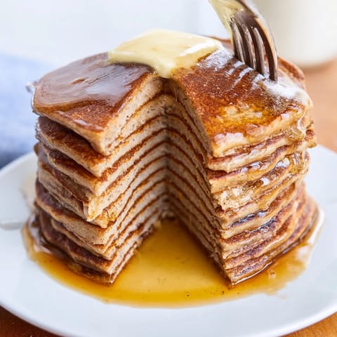 A close-up view reveals fluffy Protein Power Pancakes made with Greek yogurt, ready to be served with nut butter.  