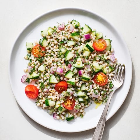 Tangy lemon vinaigrette coats the Mediterranean barley salad, garnished with fresh herbs, ready to serve as a refreshing light lunch or side dish.