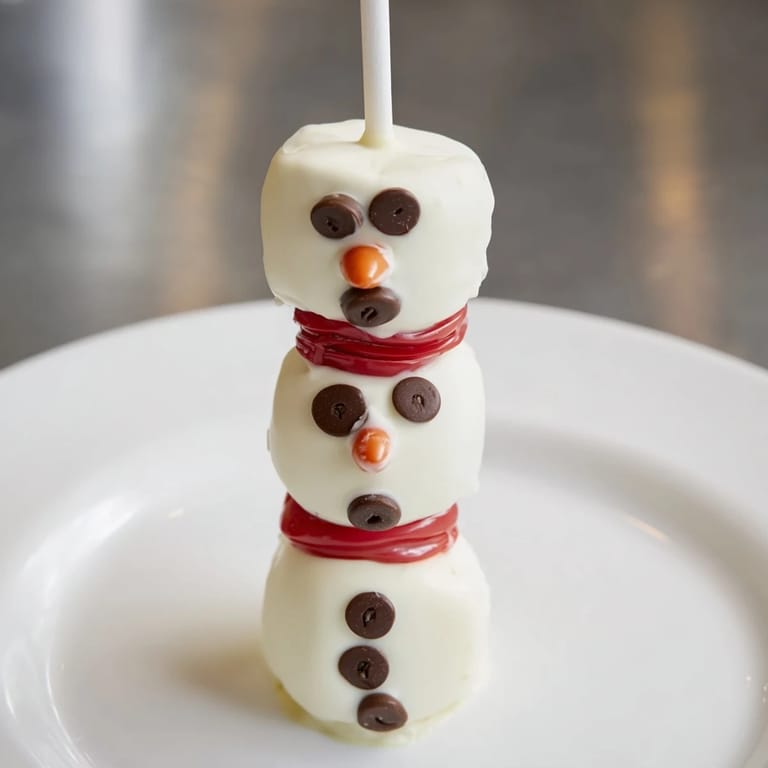 Adorable Express Snowman Marshmallow Pops, adorned with chocolate faces and colorful scarves, look delicious!