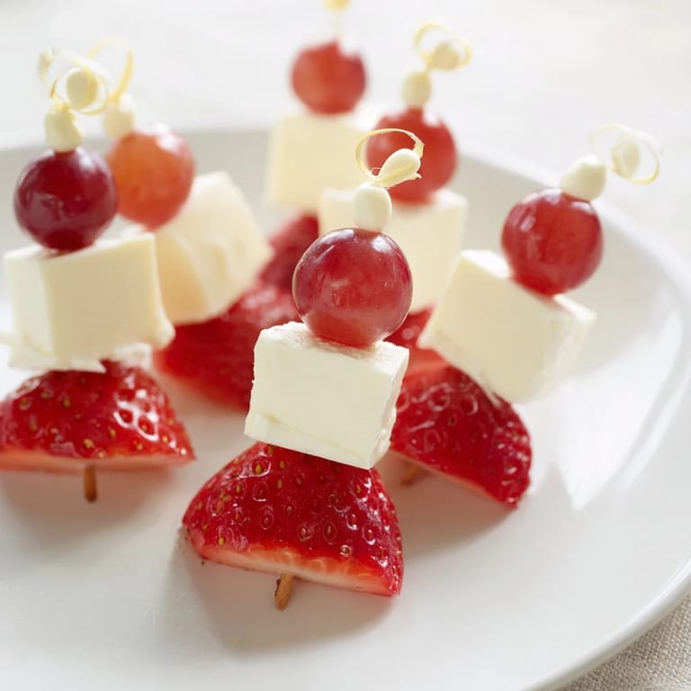 Party-ready Santa Hat Fruit and Cheese Platter shows colorful fruit arranged like festive hats; a tasty appetizer.