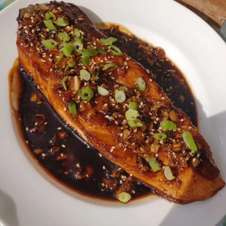 Golden-seared Ginger Soy Glazed Salmon, featuring crisp skin and coated in a flavorful sauce.