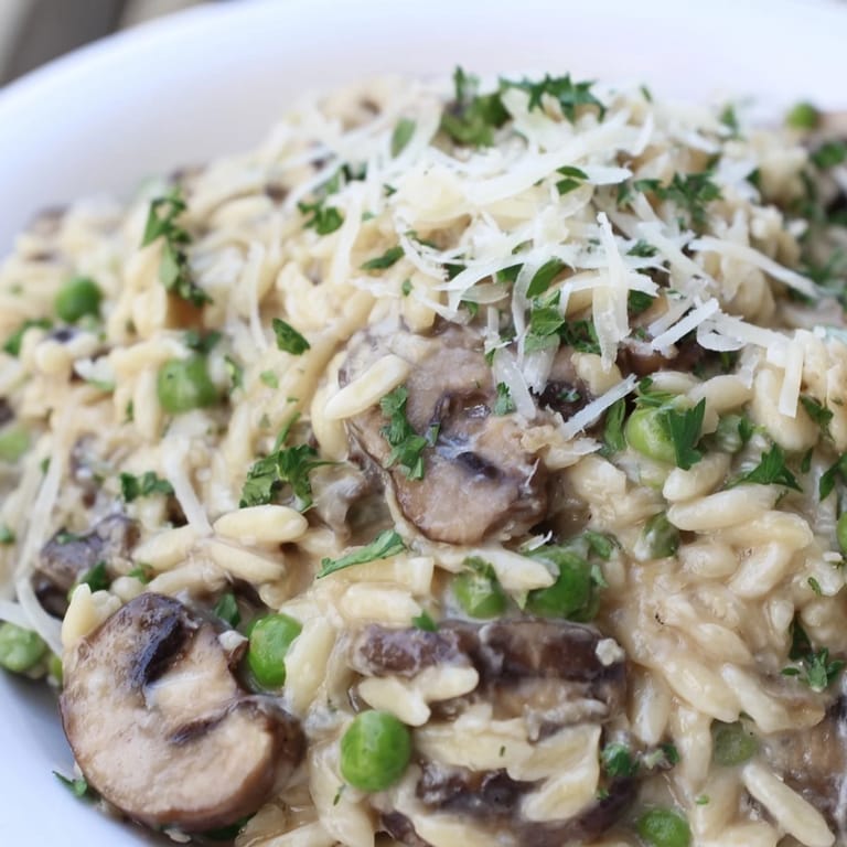 Close-up of cheesy Orzo Mushroom Risotto-Style topped with fresh herbs, ready to serve.