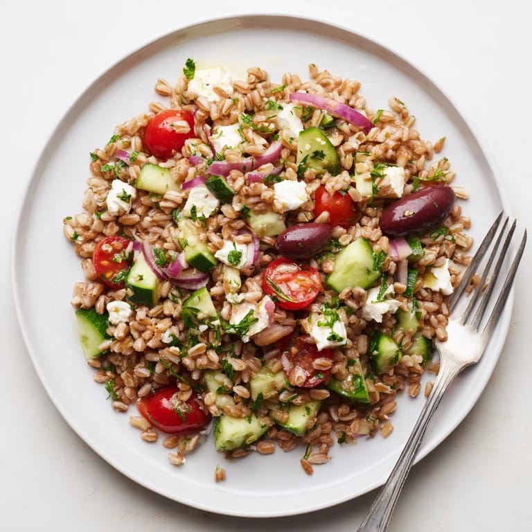 Hearty farro Mediterranean salad with chewy grains, diced cucumbers, cherry tomatoes, and feta, drizzled with tangy lemon dressing.