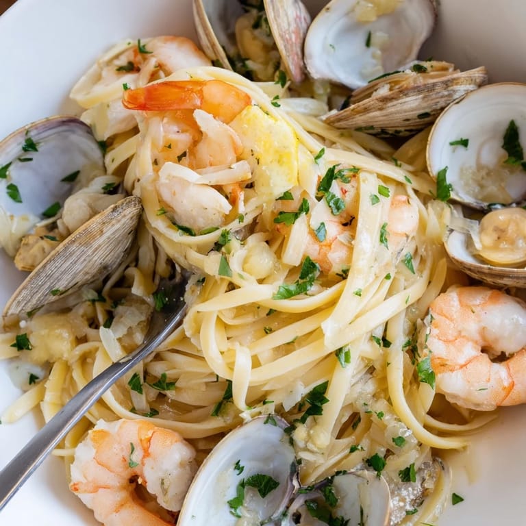 A close-up reveals plump shrimp, mussels, and clams mingled with al dente Seafood Linguine, garnished with bright lemon wedges for a zesty finish.