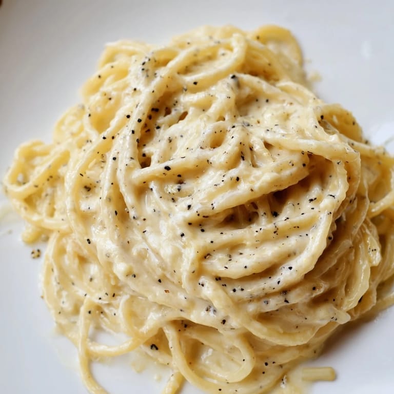 Sizzling Spaghetti Cacio e Pepe in a skillet, showcasing its simple yet luxurious Roman-inspired sauce.