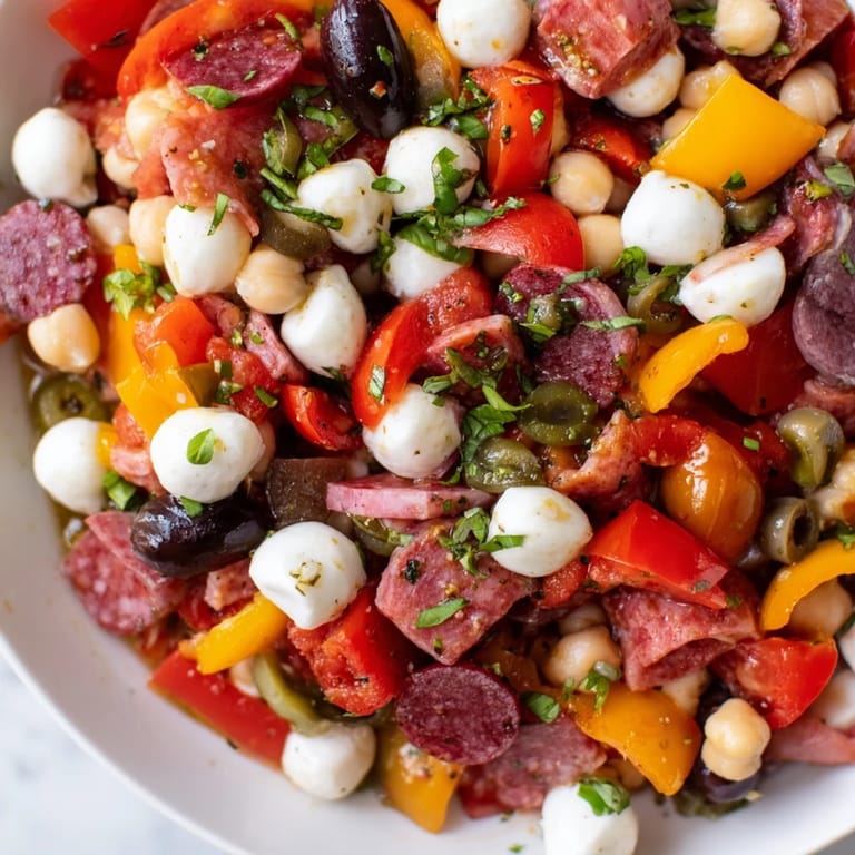 Fresh Crunchy Antipasto Chopped Salad served in a white bowl, featuring cucumbers, bell peppers, and pepperoncini.  