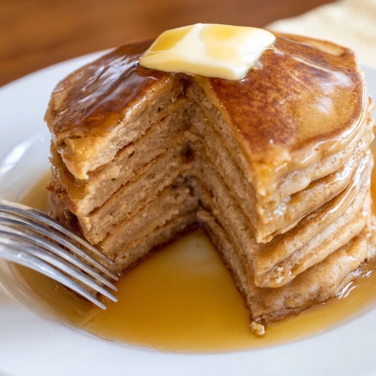A fresh serving of Protein Power Pancakes on a white plate, garnished with sliced bananas and walnuts for extra crunch.