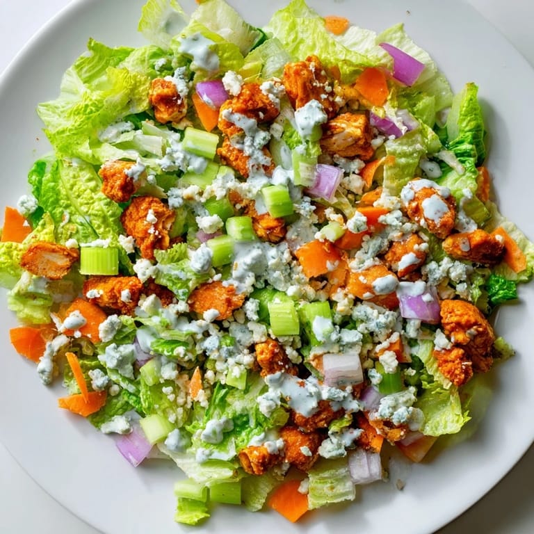 Close-up of Buffalo Chicken Chopped Salad, featuring juicy red tomatoes, diced celery, and blue cheese on crunchy lettuce.