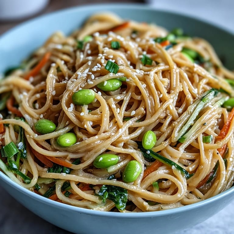 Creamy sesame ginger dressing coats cold noodles in this refreshing Asian-inspired bowl, garnished with julienned vegetables and green onions.