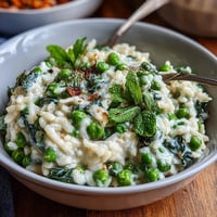 A creamy, vibrant risotto with fresh peas and mint, topped with Parmesan for a spring dinner party.