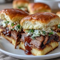 Tender, smoky brisket piled high on soft slider buns, drizzled with tangy BBQ sauce and topped with crisp, fresh slaw.  