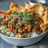 Fork-tender ground chicken and crisp veggies mingle over fluffy rice in this Crispy Baked Egg Roll Chicken Bowl.