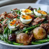 A colorful spring Niçoise salad with tuna, green beans, and soft-boiled eggs drizzled with tangy Dijon vinaigrette.  